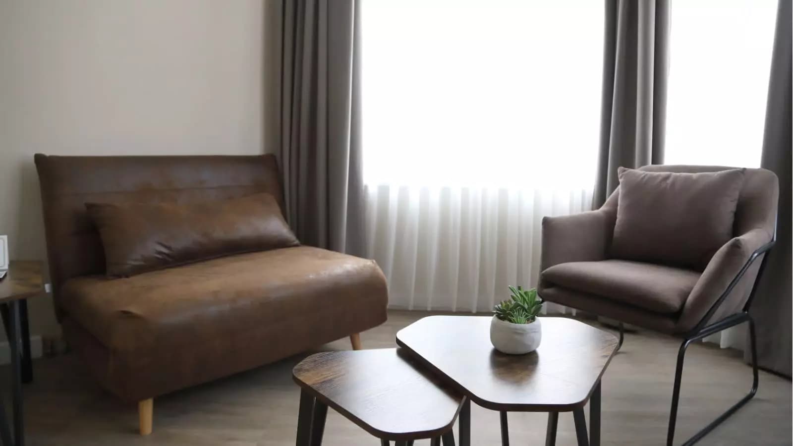 Gemütliche Sitzecke mit braunem Ledersofa, Sessel und kleinen Beistelltischen