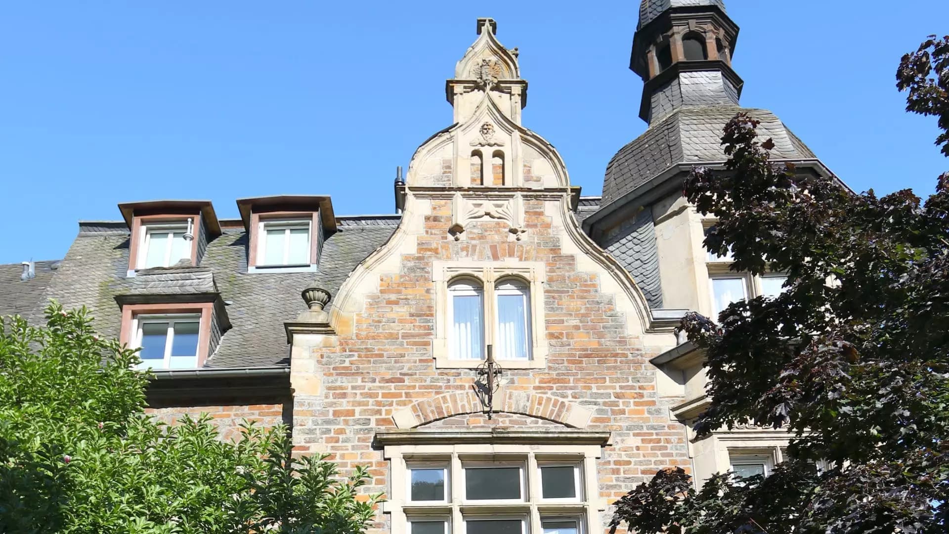 Turm und Zwerchgiebel der Moselvilla im Detail vor blauem Himmel