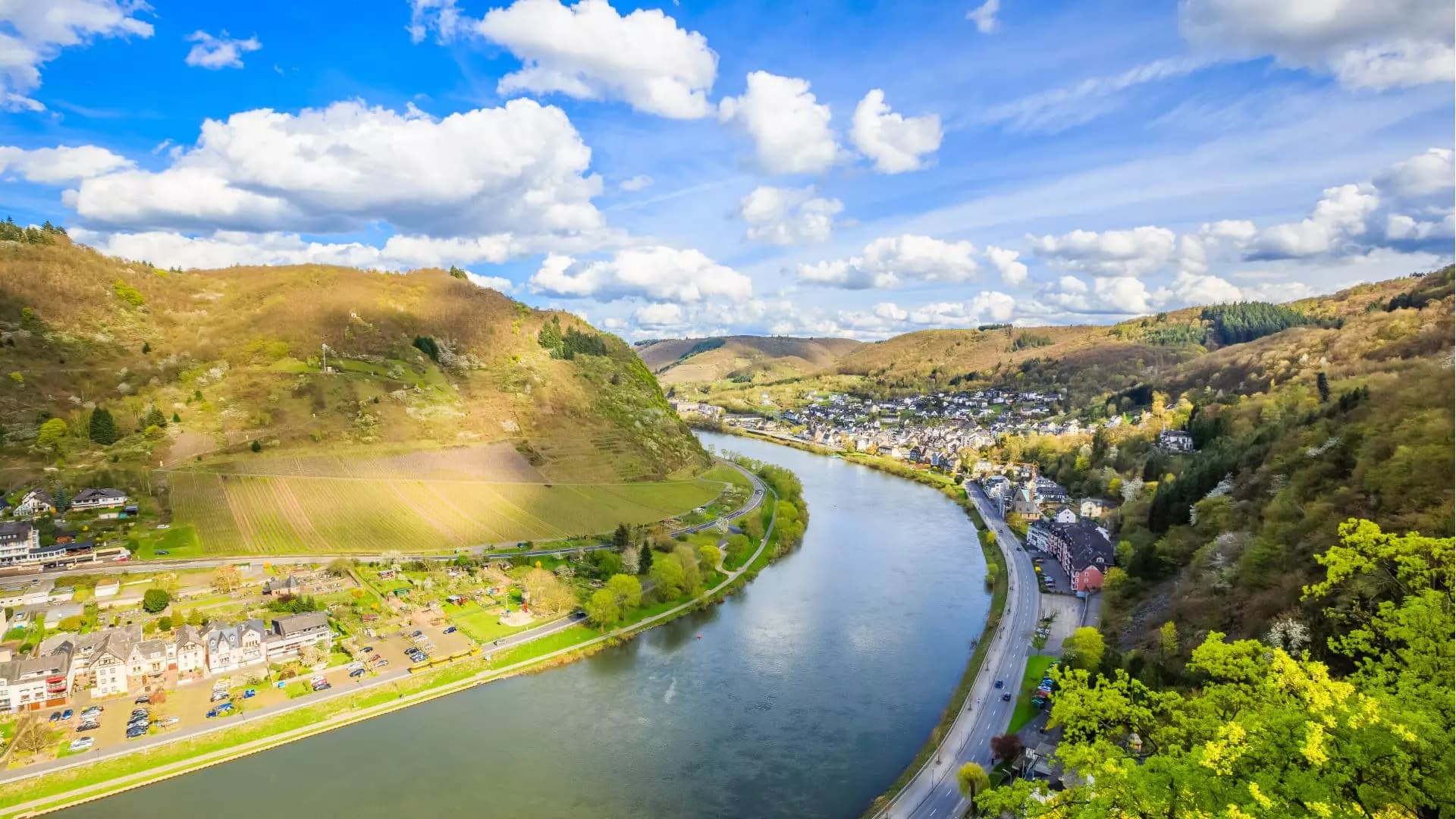 Panoramablick auf die Moselschleife mit Ortschaft, Weinbergen und bewaldeten Hügeln