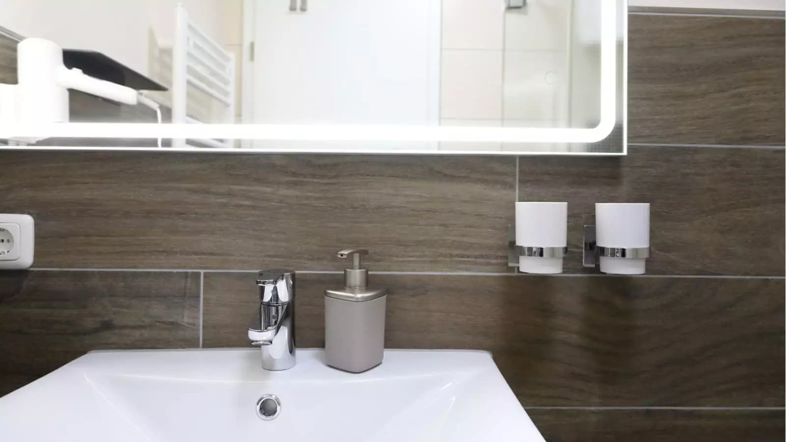 Modernes Badezimmer mit Waschbecken, Seifenspender und beleuchtetem Spiegel