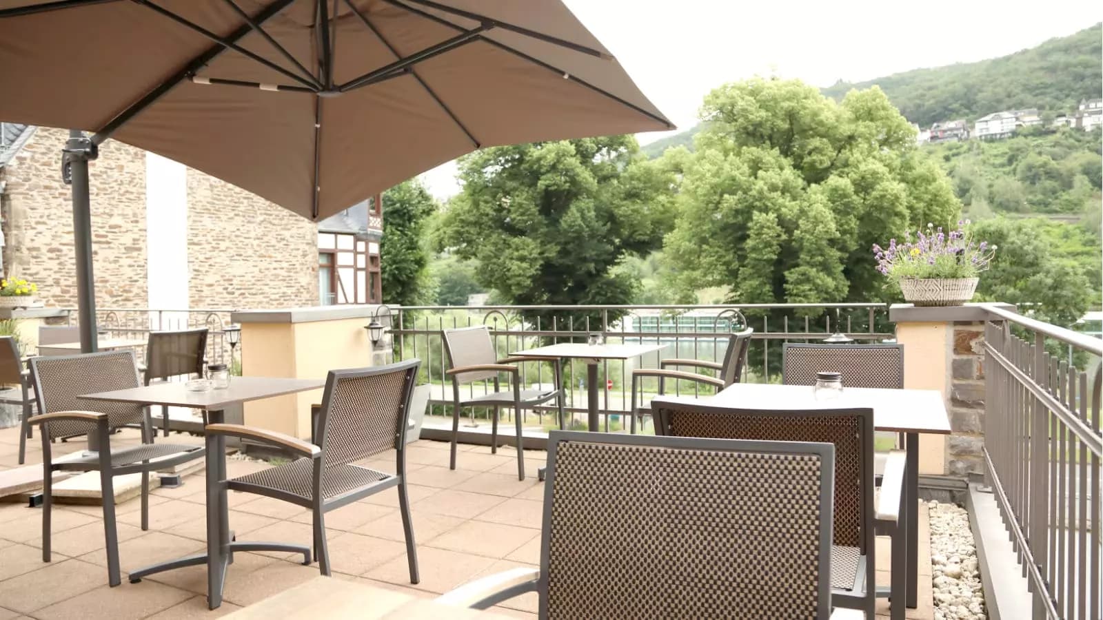 Terrasse mit Sonnenschirm und Sitzgruppen mit Blick auf die Mosel und bewaldete Hänge
