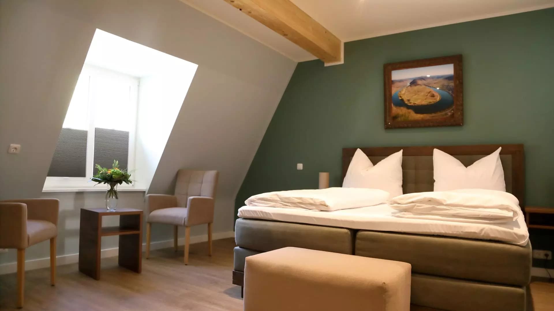 Dachzimmer mit salbeigrüner Wand, gerahmtem Landschaftsfoto und gepolstertem Sessel