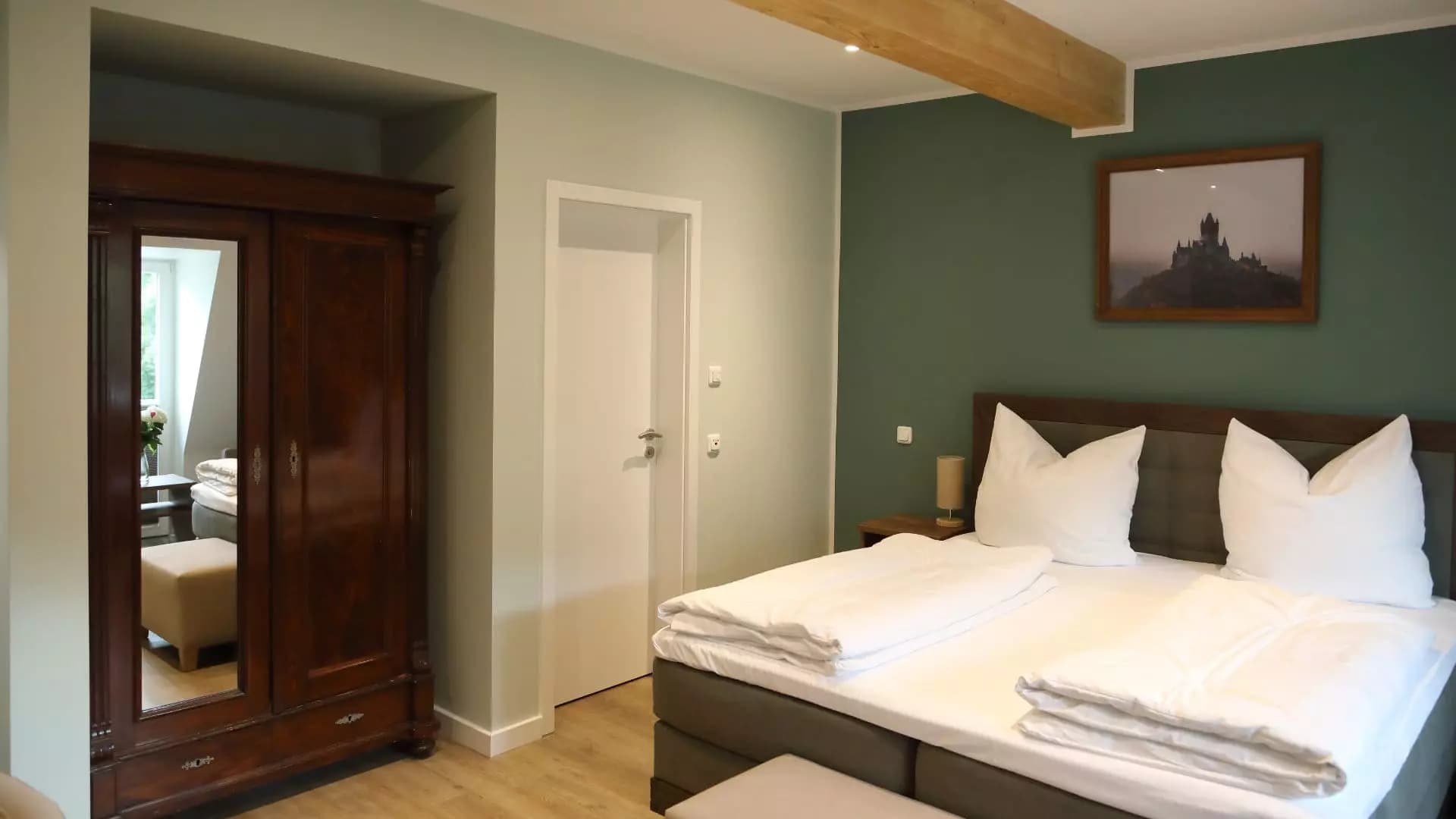 Zimmer mit blauer Wand, Backsteinnische und Foto der Moselschleife über dem Bett